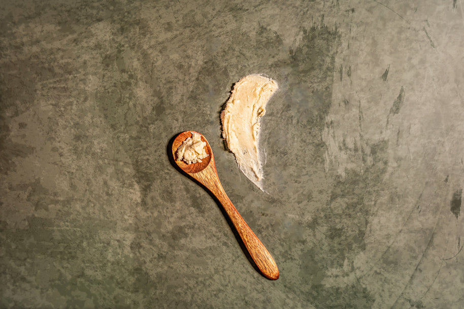Wooden spoon with a scoop of tea butter on a textured dark surface