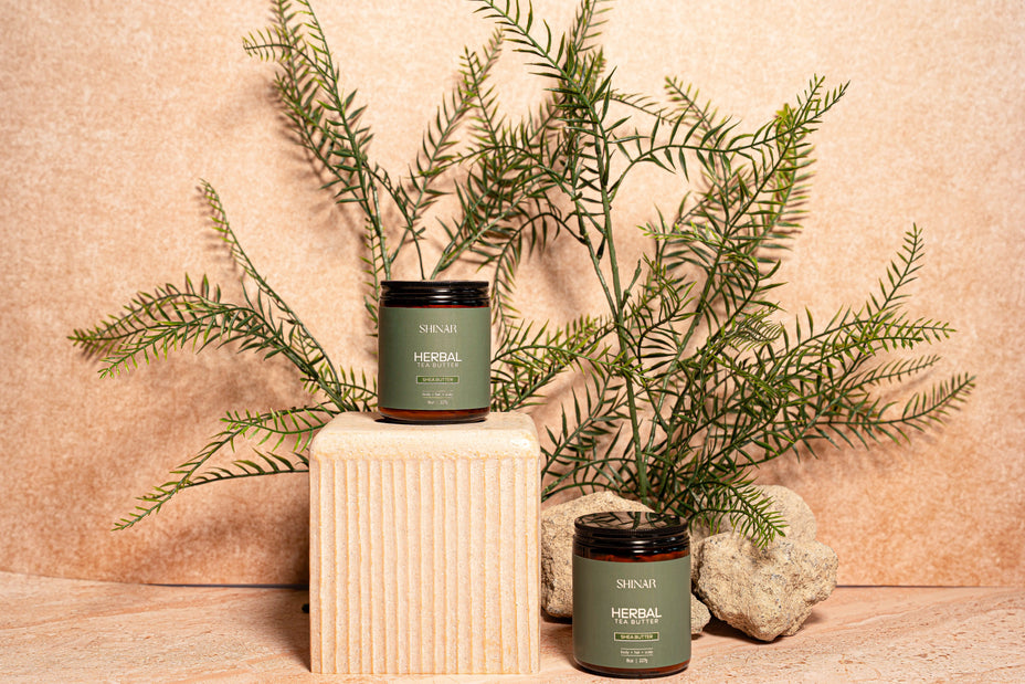 Two jaras labeled 'Herbal' on wooden blocks with green leaves and stones in the background