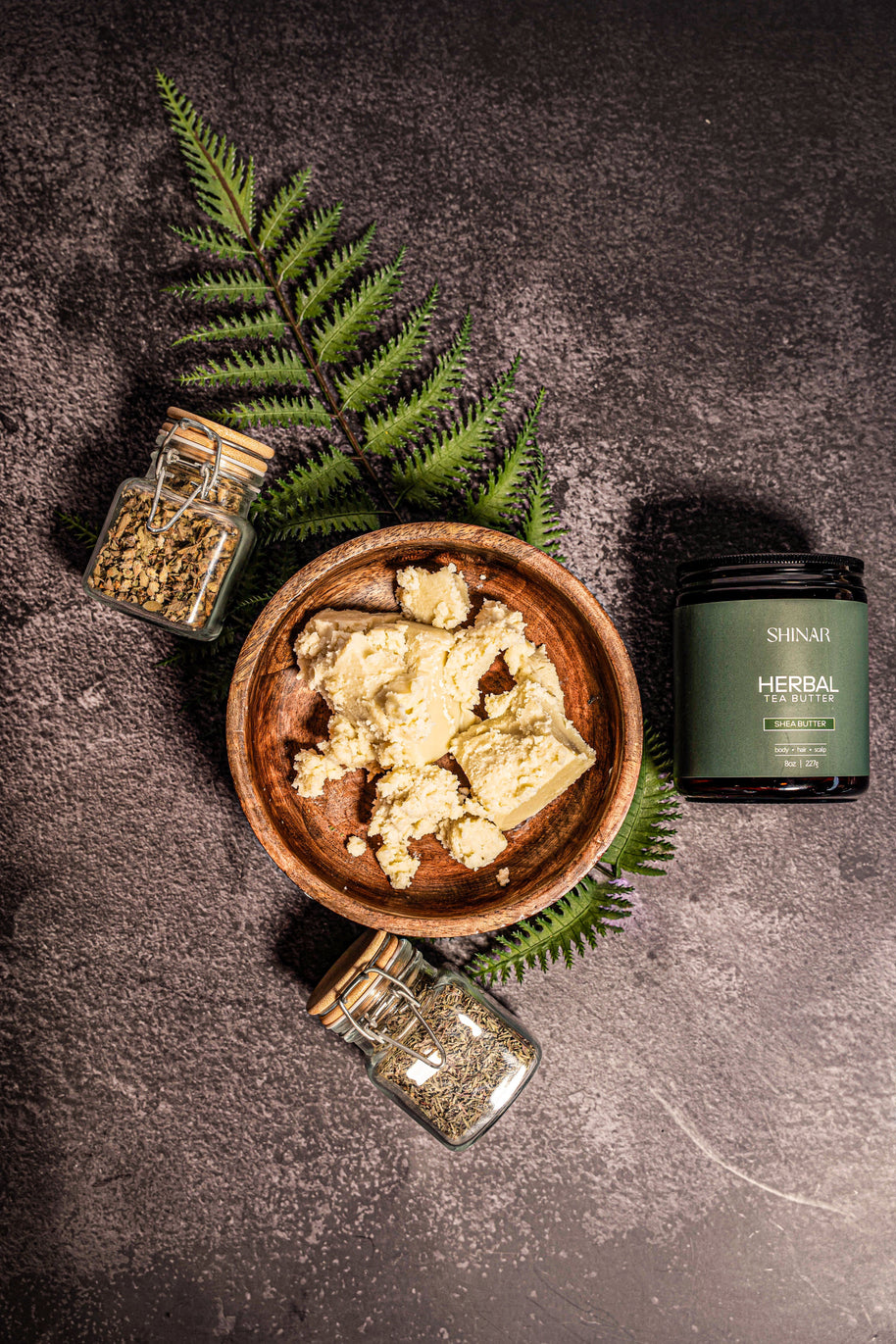 Herbal product in a wooden bowl with jars and fern leaves on a dark surface