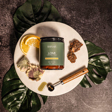 A jar of Shinar Lomi butter on a white plate with lemon slices, and a spoon on a dark background.