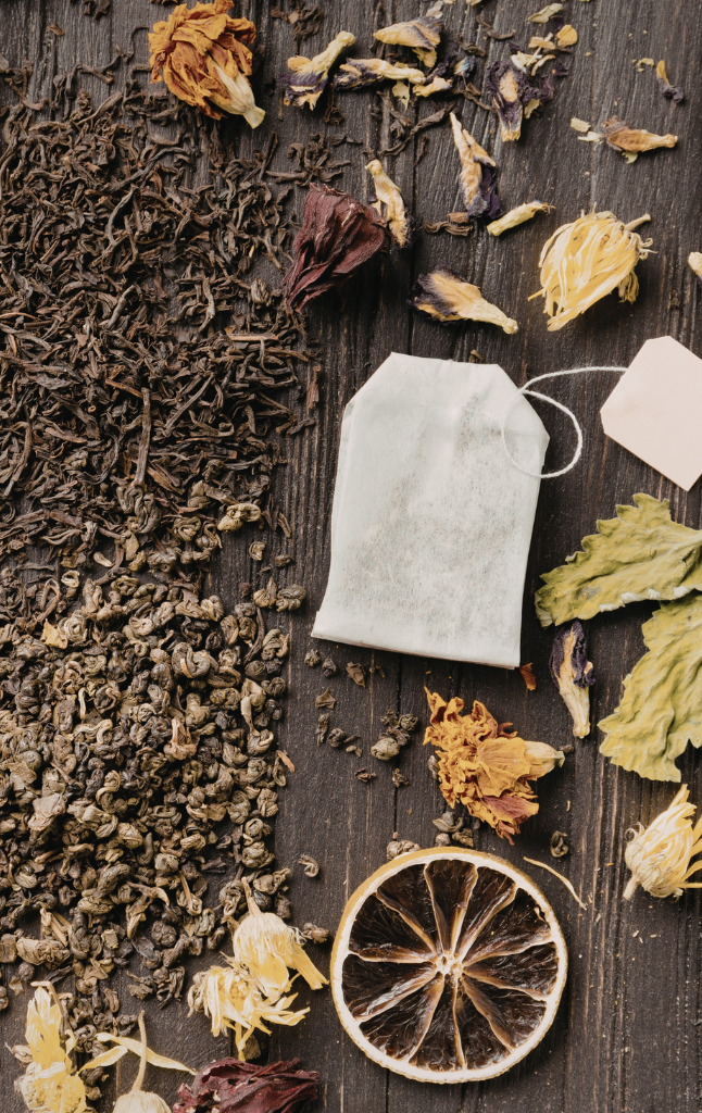 Tea leaves, tea bags, and dried herbs on a wooden surface